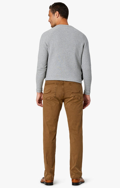 A man stands with his back to the camera, wearing a light gray sweater and 34 Heritage Tobacco Twill comfort rise, straight leg pants by 34 Heritage against a plain white background.