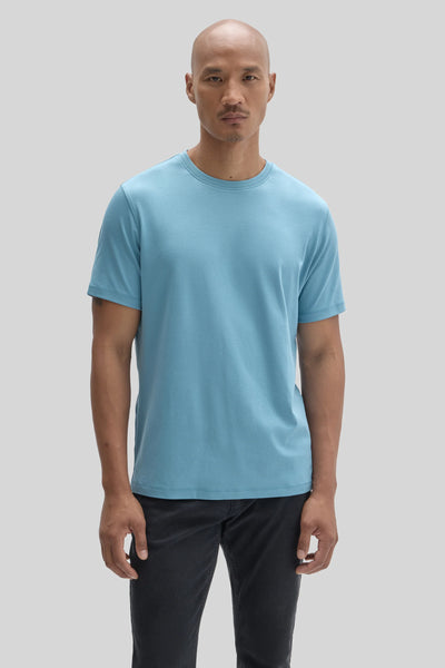 A man wearing a light blue Robert Barakett Tee Shirt Georgia Crew 23336 and dark jeans.