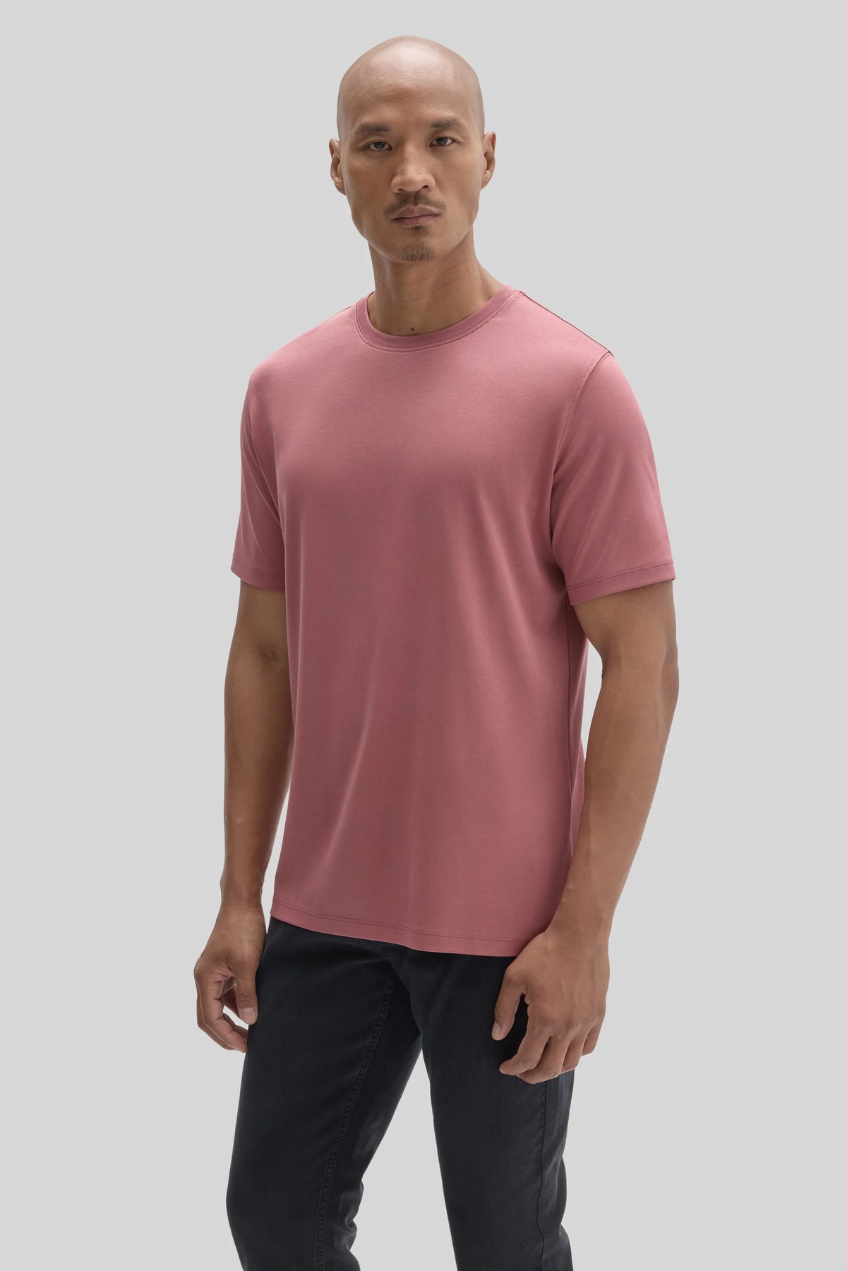 A man wearing a dusty pink Robert Barakett Tee Shirt Georgia Crew 23336 and black jeans.