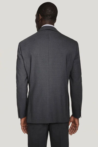 Back view of a man in the Jack Victor Solid Wool Suit jacket—wrinkle-resistant charcoal grey wool—paired with a white shirt, by Jack Victor, shown against a light grey background.