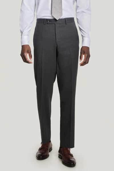 A person in the Jack Victor Solid Wool Suit by Jack Victor, paired with a white shirt, light grey tie, and brown dress shoes, stands against a plain light background. The suit offers stretch comfort and wrinkle resistance for all-day sharpness.