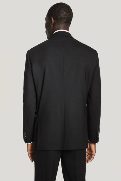 A man in a Jack Victor Solid Wool Suit stands facing away from the camera against a plain light background.