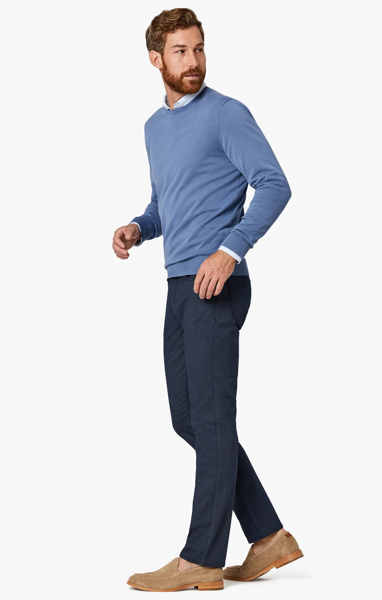 Man wearing a blue sweater and navy pants on a white background