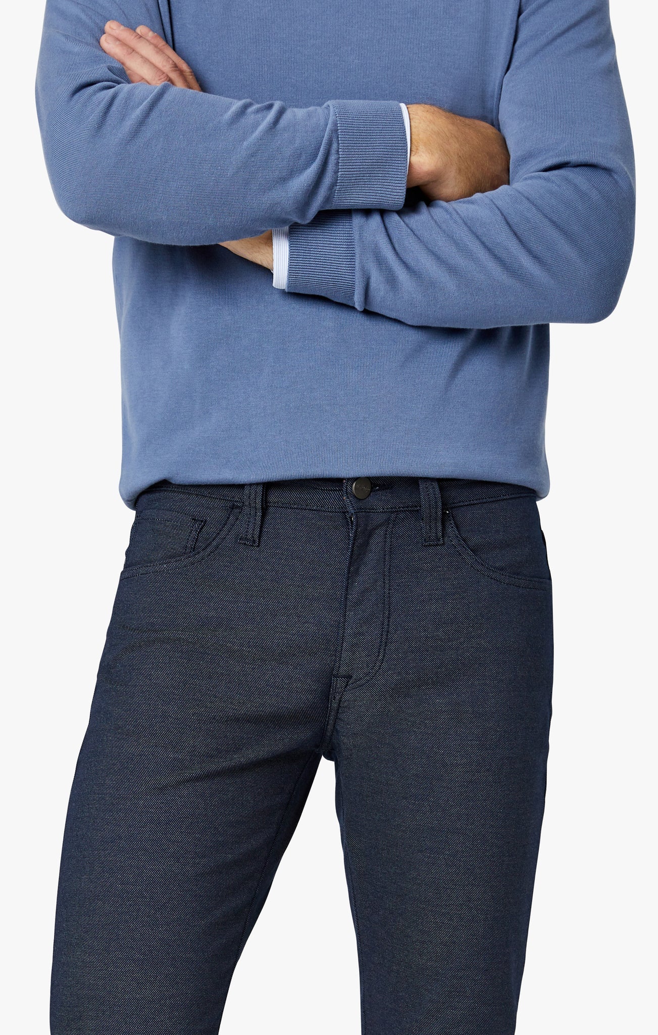 Person wearing a blue sweater and dark pants on a white background