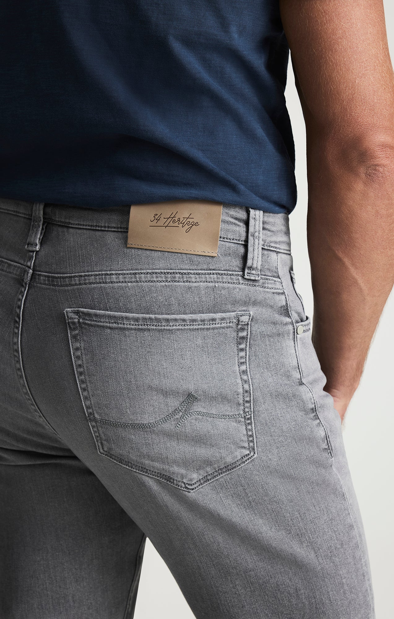 Person wearing gray jeans with a visible brand label on a white background