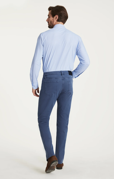 Man wearing a light blue shirt and dark blue pants on a white background