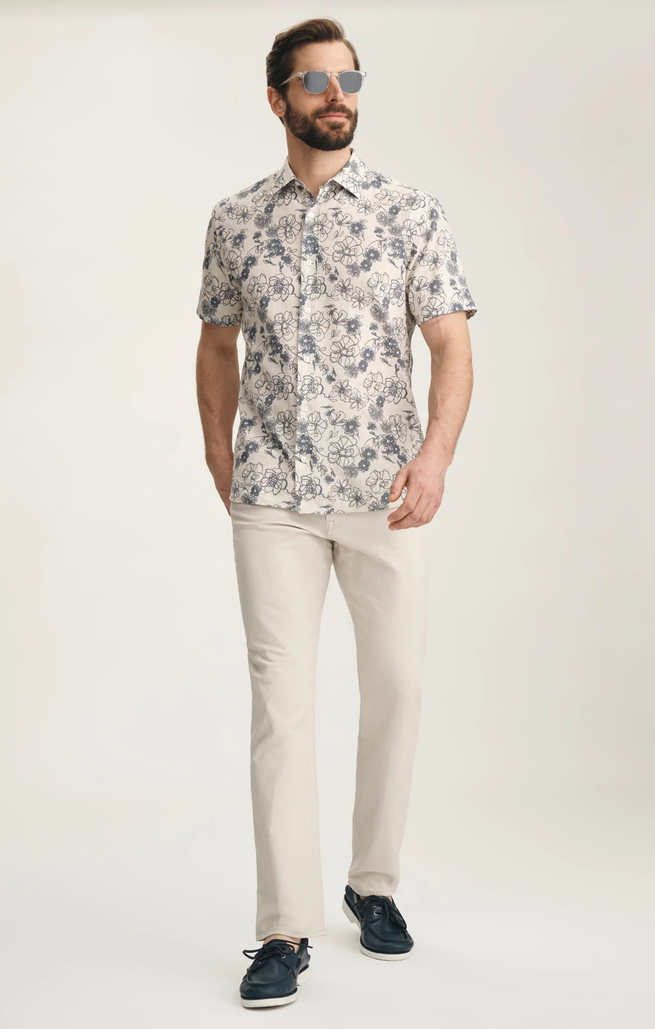 Man wearing a patterned shirt and beige pants on a white background