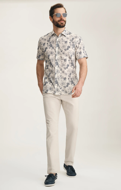Man wearing a patterned shirt and beige pants on a white background