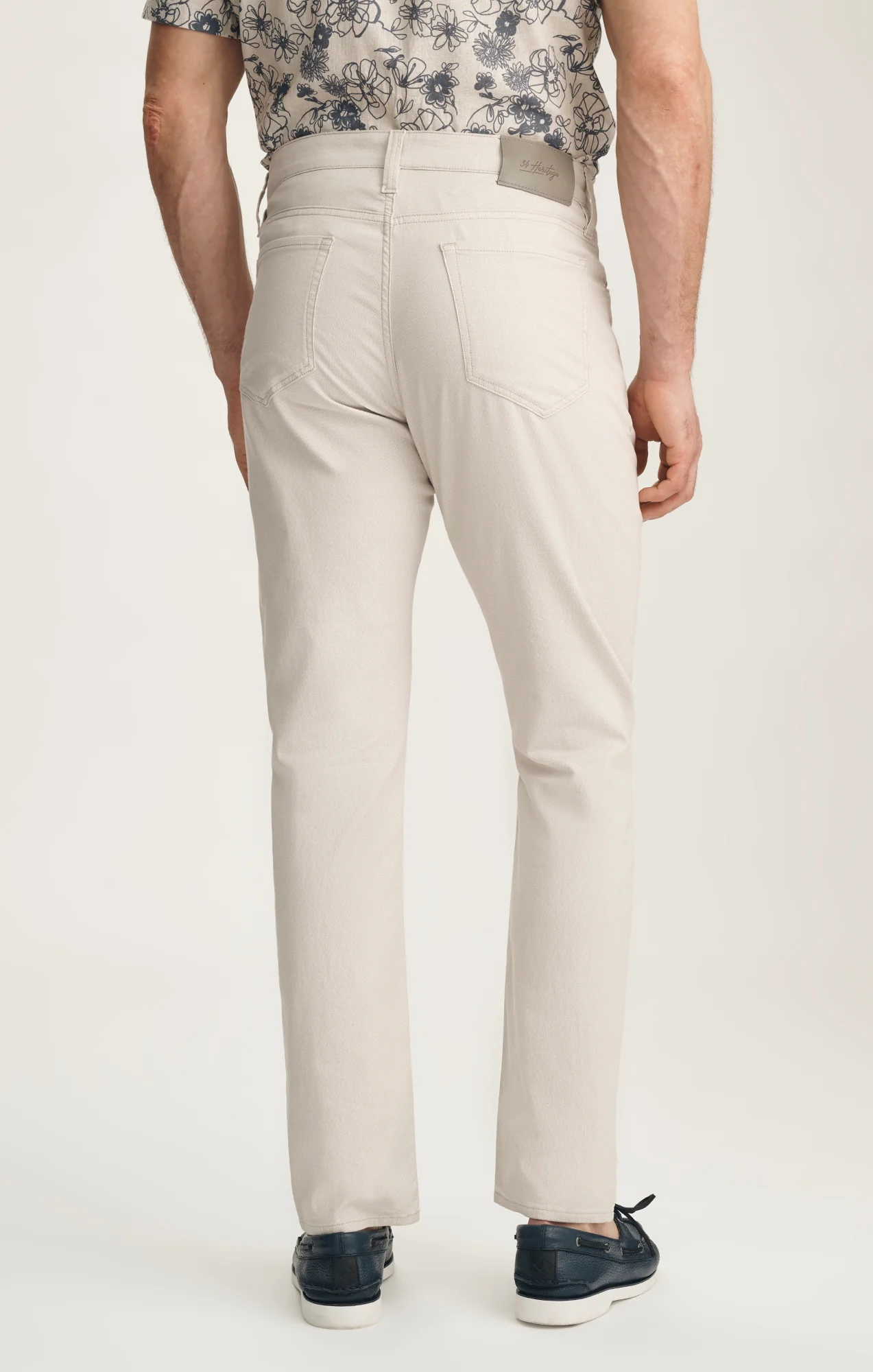 Person wearing beige pants with a floral top on a white background