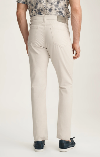 Person wearing beige pants with a floral top on a white background