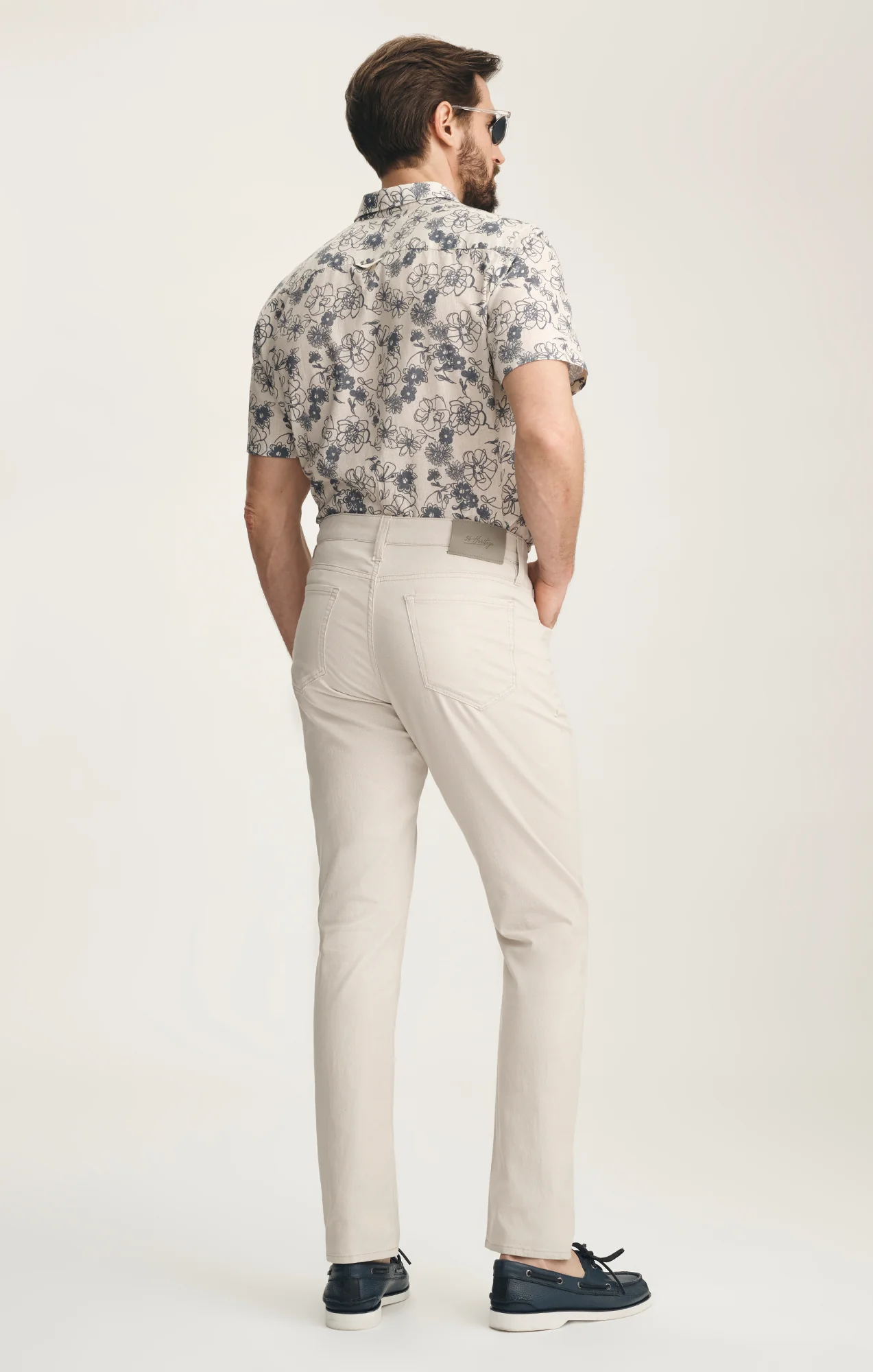 Man wearing a floral shirt and beige pants on a white background