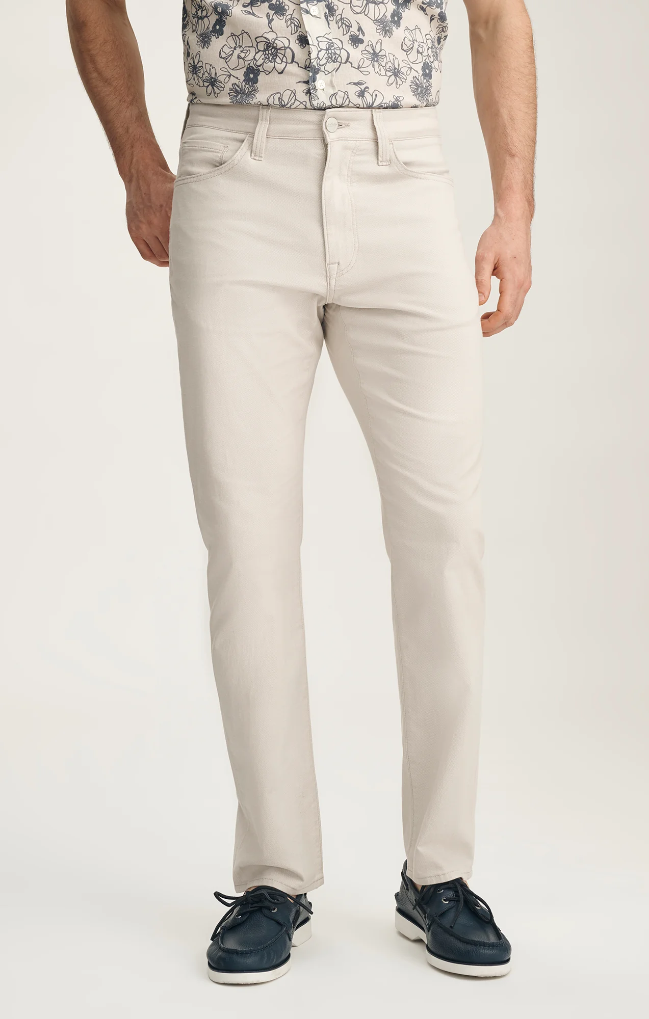 Person wearing light-colored pants and a patterned shirt on a white background