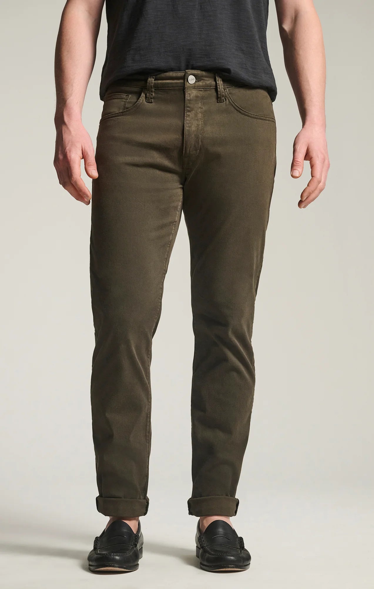 A person stands facing forward against a plain background, wearing 34 Heritage Courage Twill Pants in olive green, paired with a dark t-shirt and black shoes.