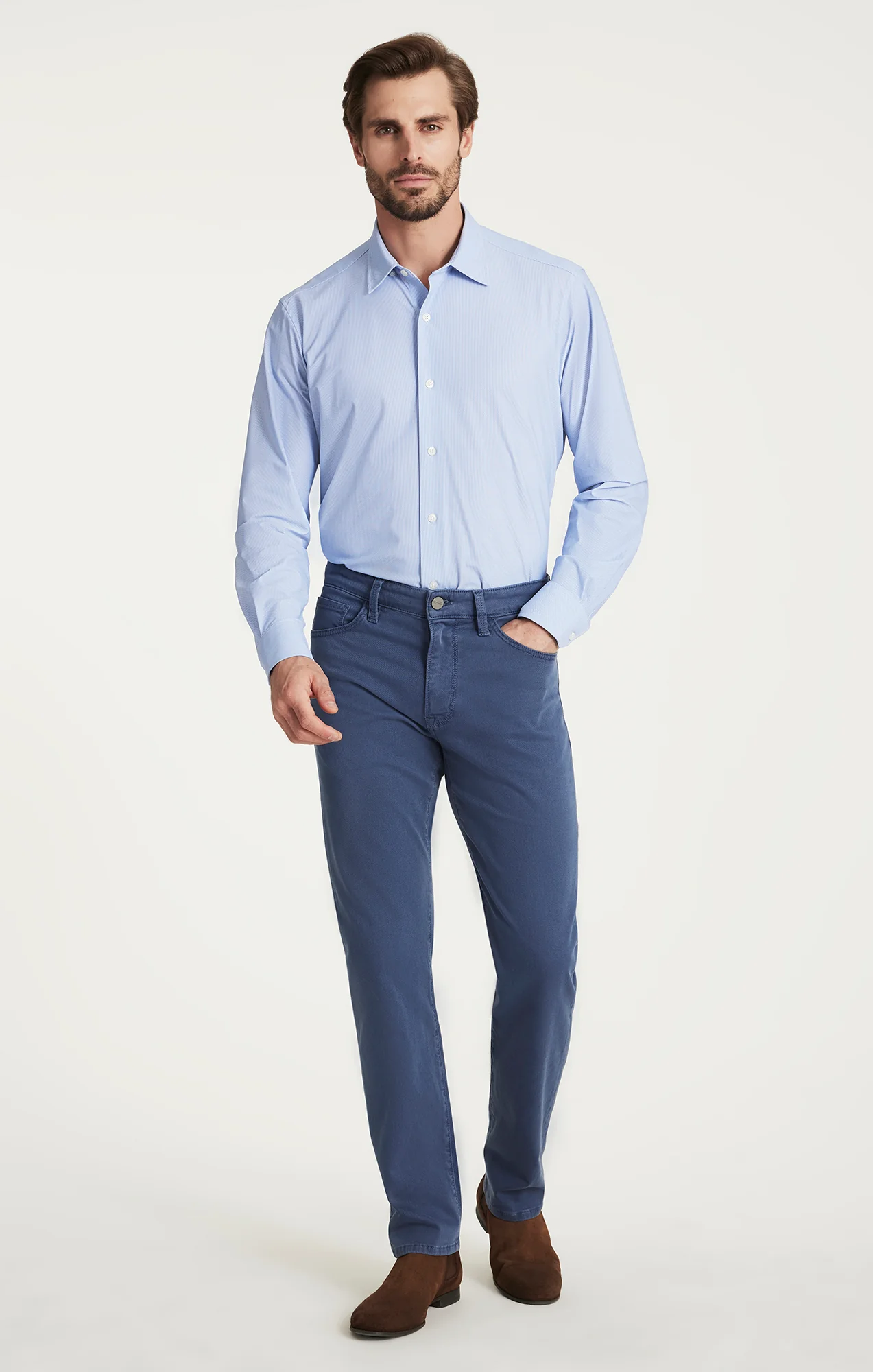 Man wearing a light blue dress shirt and dark blue pants on a white background