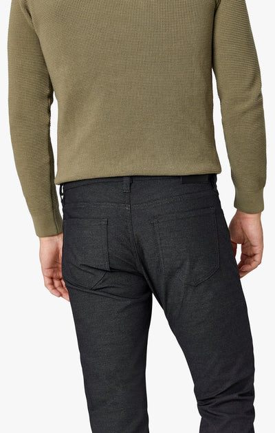 A person shown from the back wearing a textured olive green long-sleeve shirt and 34 Heritage Courage Coolmax modern straight leg dark denim jeans, with hands relaxed at their sides.