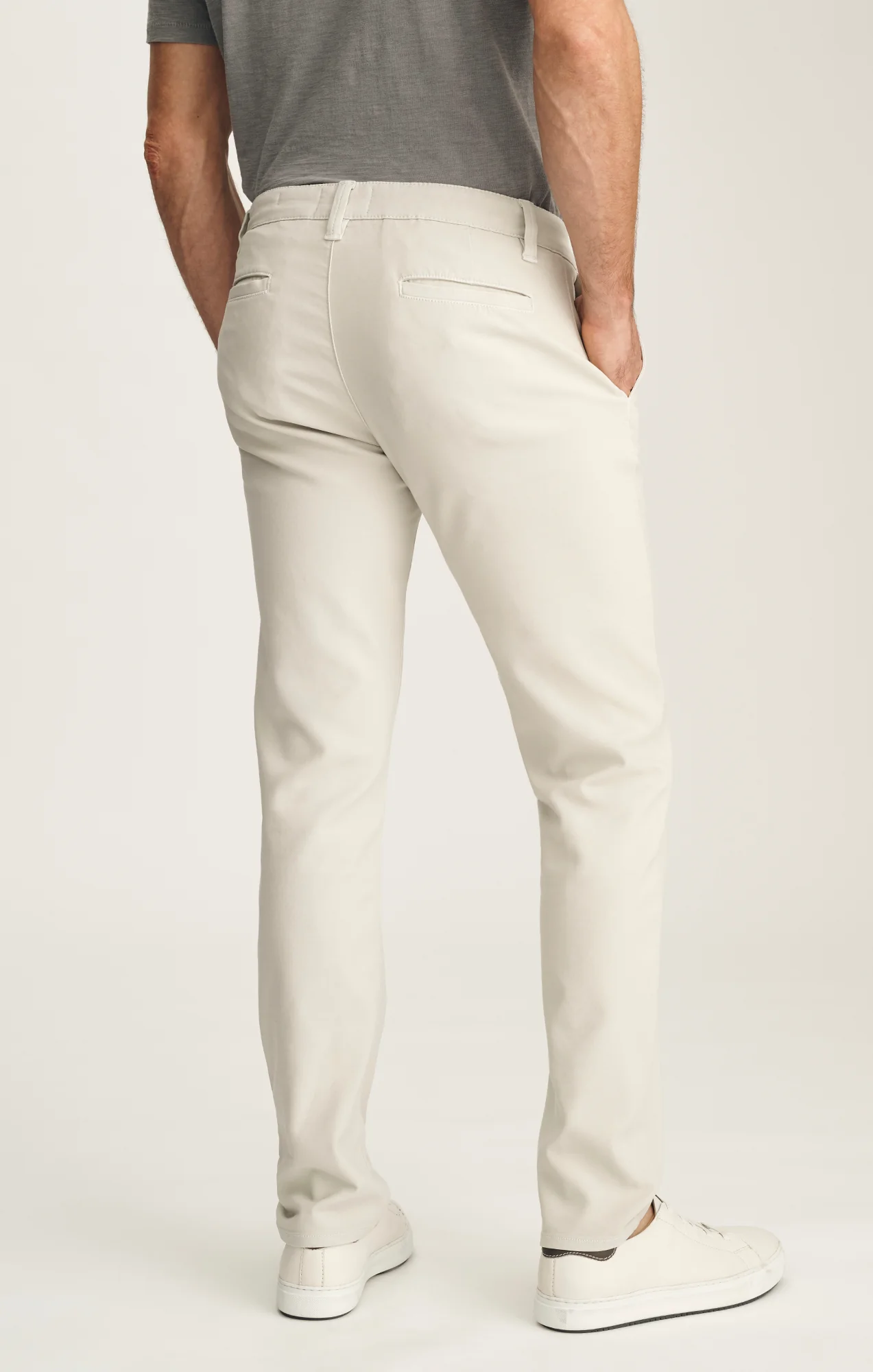 Person wearing light-colored pants and a gray shirt on a white background