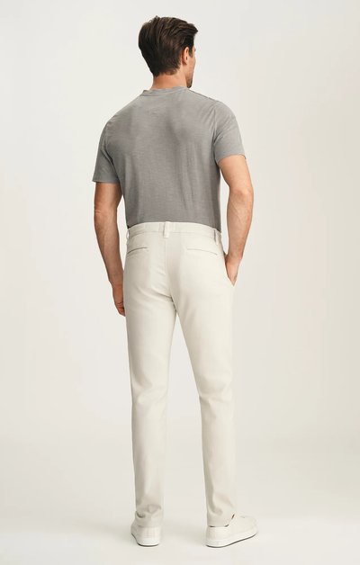 Man wearing a gray polo shirt and white pants on a plain background
