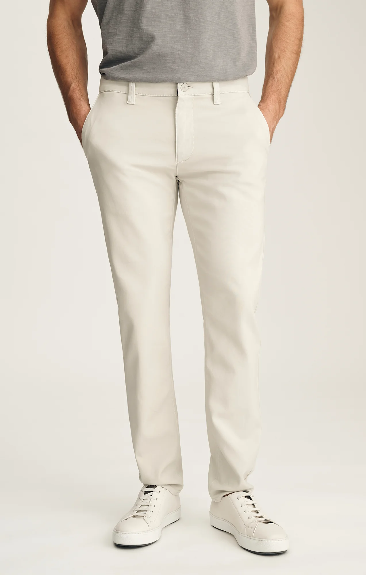 Person wearing light-colored pants and a gray shirt on a plain background