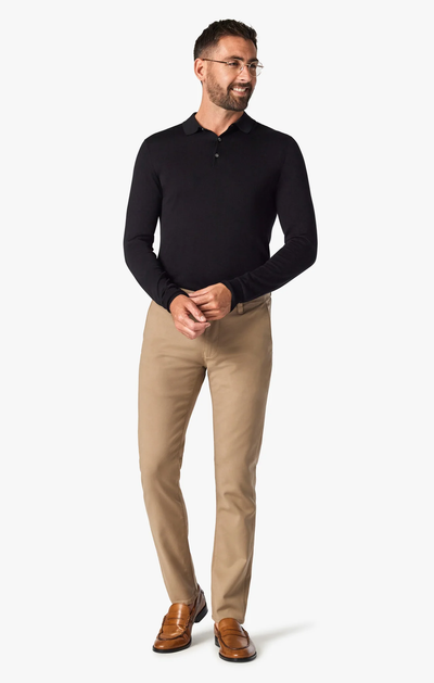 Man wearing a black long-sleeve shirt and beige pants on a white background