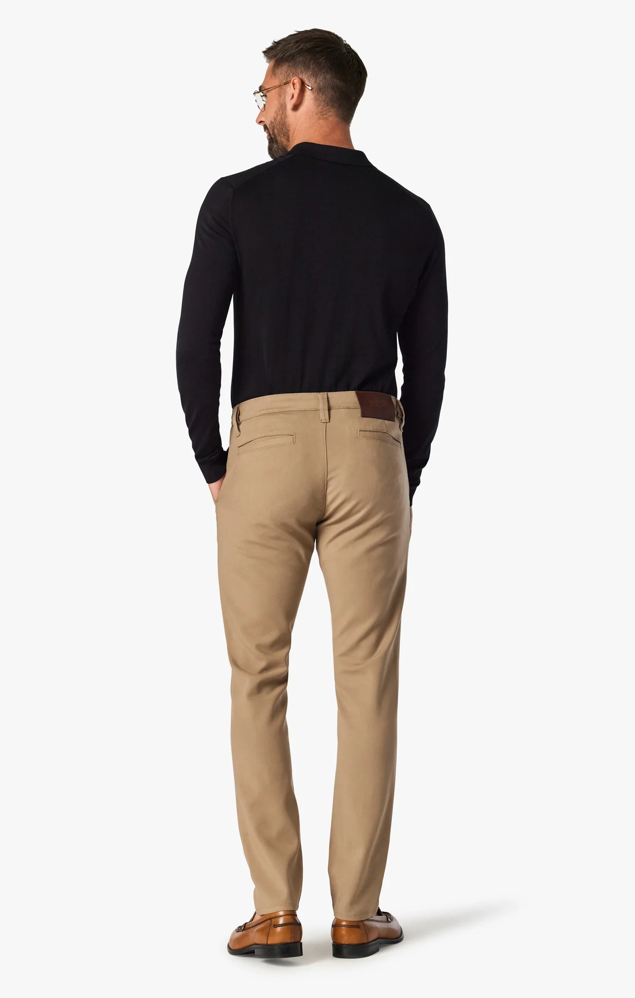 Man wearing a black sweater and beige pants on a white background