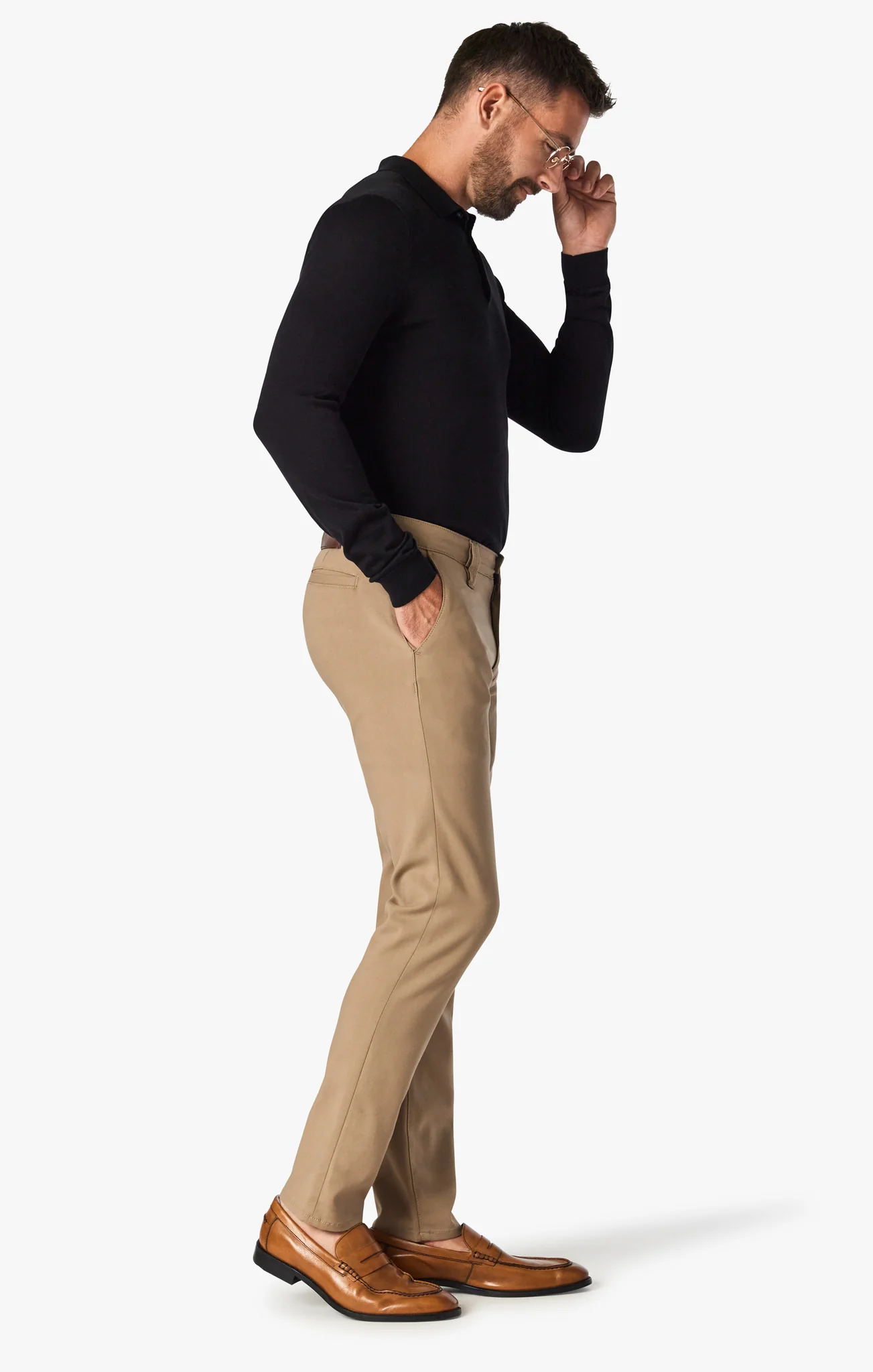 Man wearing a black sweater, beige pants, and brown shoes on a white background