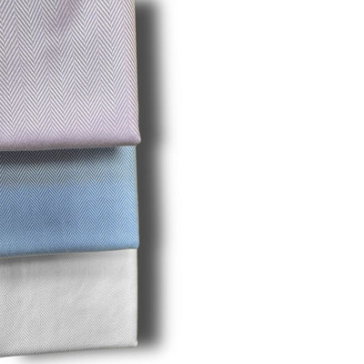 Three neatly folded, wrinkle-free Wilkes & Riley Herringbone Dress Shirts in light purple, blue, and white are stacked vertically against a white background.