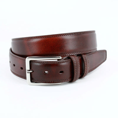 The Torino Hand Antiqued Italian Calfskin Belt by Torino features brown Italian calfskin leather and a silver rectangular buckle, elegantly coiled on a white background.
