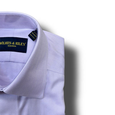 A neatly folded Wilkes & Riley Herringbone Dress Shirt for Big & Tall, made from light purple Supima cotton with a non-iron finish, offers ultimate wrinkle-free convenience.