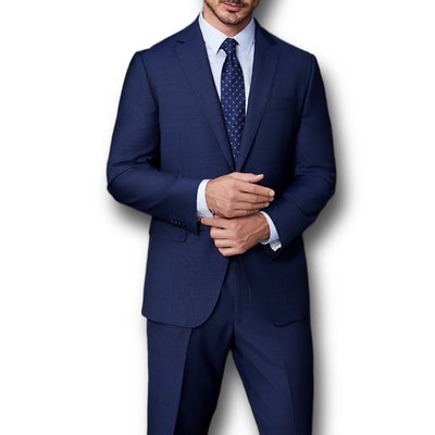A man wears the Paul Betenly Solid Suit - Slim Fit by Paul Betenly with a light blue shirt and navy polka dot tie, posing against a plain white background, shown from shoulders to knees.