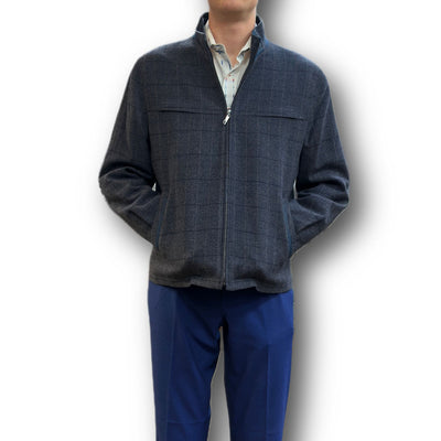 Man in a gray Enzo Coat Play by Enzo, featuring a subtle plaid pattern, worn over a light shirt and blue pants, standing with hands in pockets against a white background.