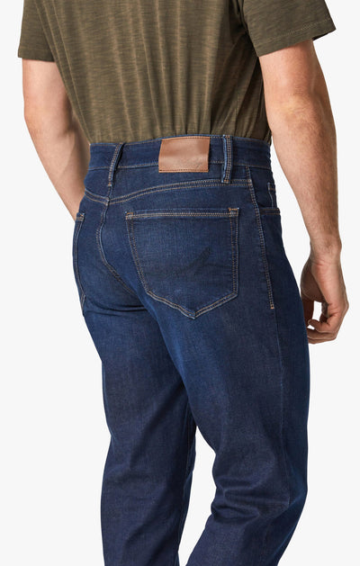 Someone shown from the back waist down wears a green short-sleeve shirt and 34 Heritage Dark Cashmere straight leg, high rise jeans by 34 Heritage, featuring a brown patch on the waistband.