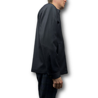 A model in the Mattarazi Coat Paolo by Mattarazi—a dark, long-sleeve tailored men's coat—paired with plaid trousers, shown from the side against a white background.