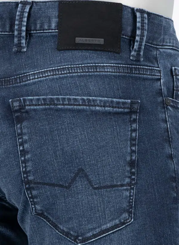 Close-up of blue denim jeans with alberto brand label on the back pocket.