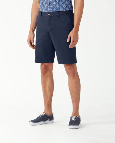 A person stands on a white background wearing a patterned blue shirt, Tommy Bahama Boracay Shorts Big & Tall, and blue canvas shoes.