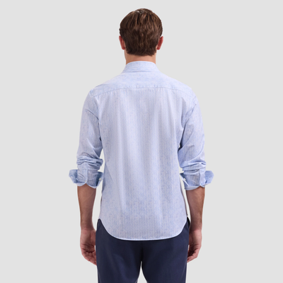 Man wearing a light blue striped shirt and dark pants on a plain background