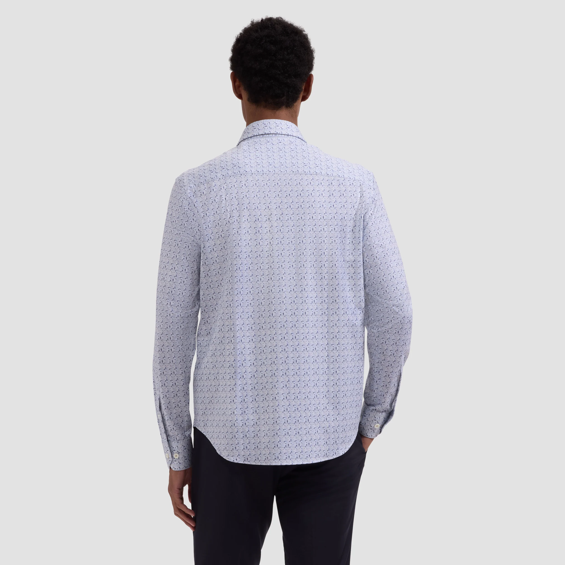 Person wearing a patterned shirt from behind on a plain background