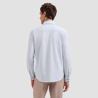 Man wearing a light blue shirt and beige pants on a plain background