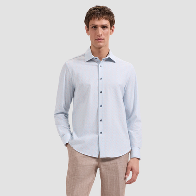 Man wearing a light blue checkered shirt and beige pants on a white background