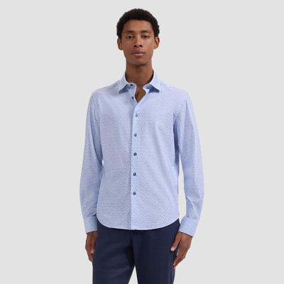 Man wearing a light blue patterned shirt and dark pants on a white background
