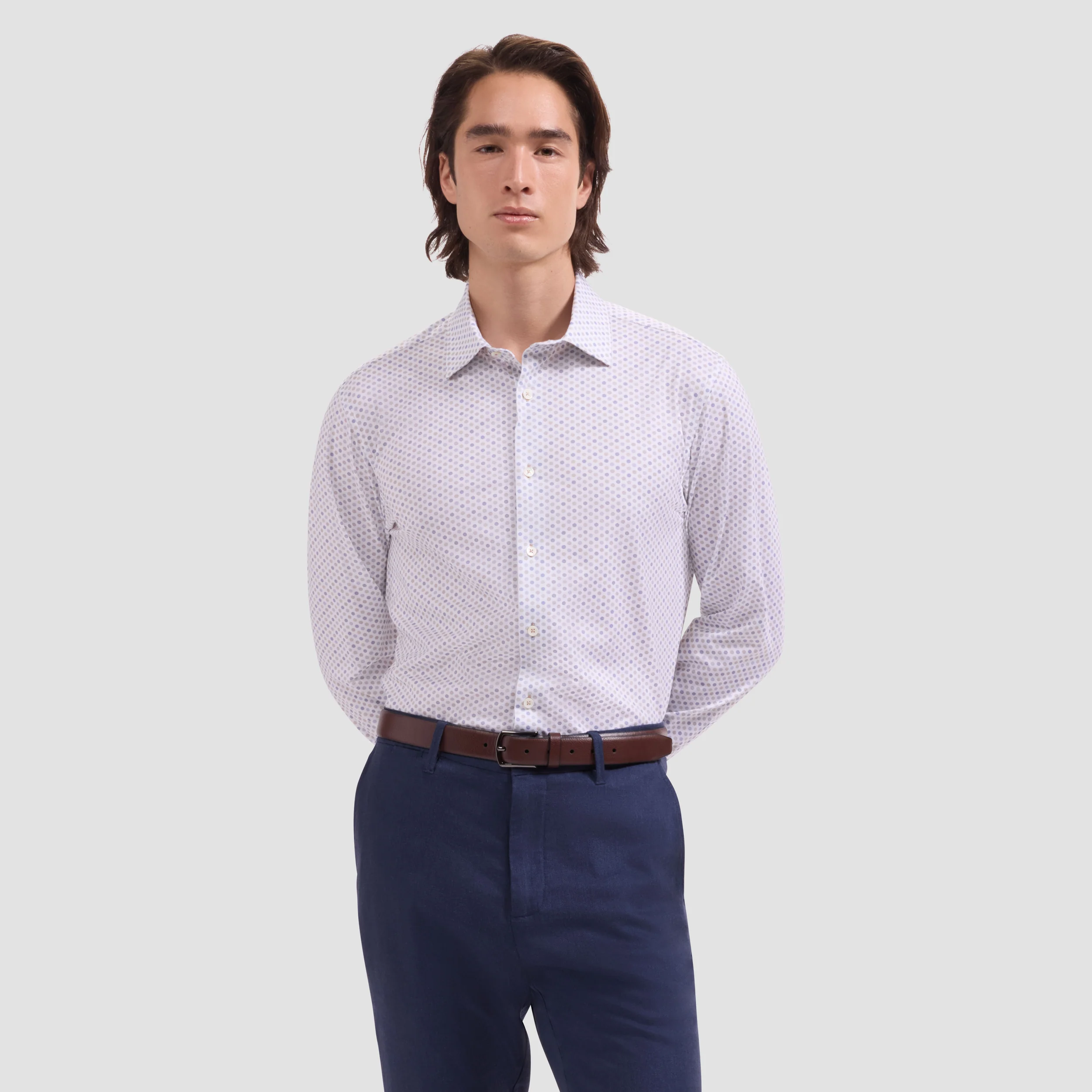 Man wearing a patterned shirt and navy pants on a light gray background