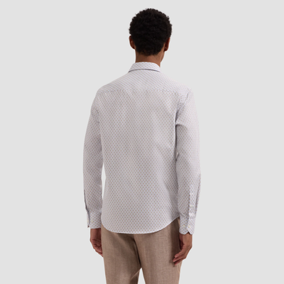 Man wearing a patterned shirt and beige pants on a light gray background