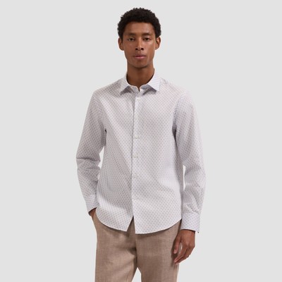 Man wearing a patterned white shirt with beige pants on a light gray background