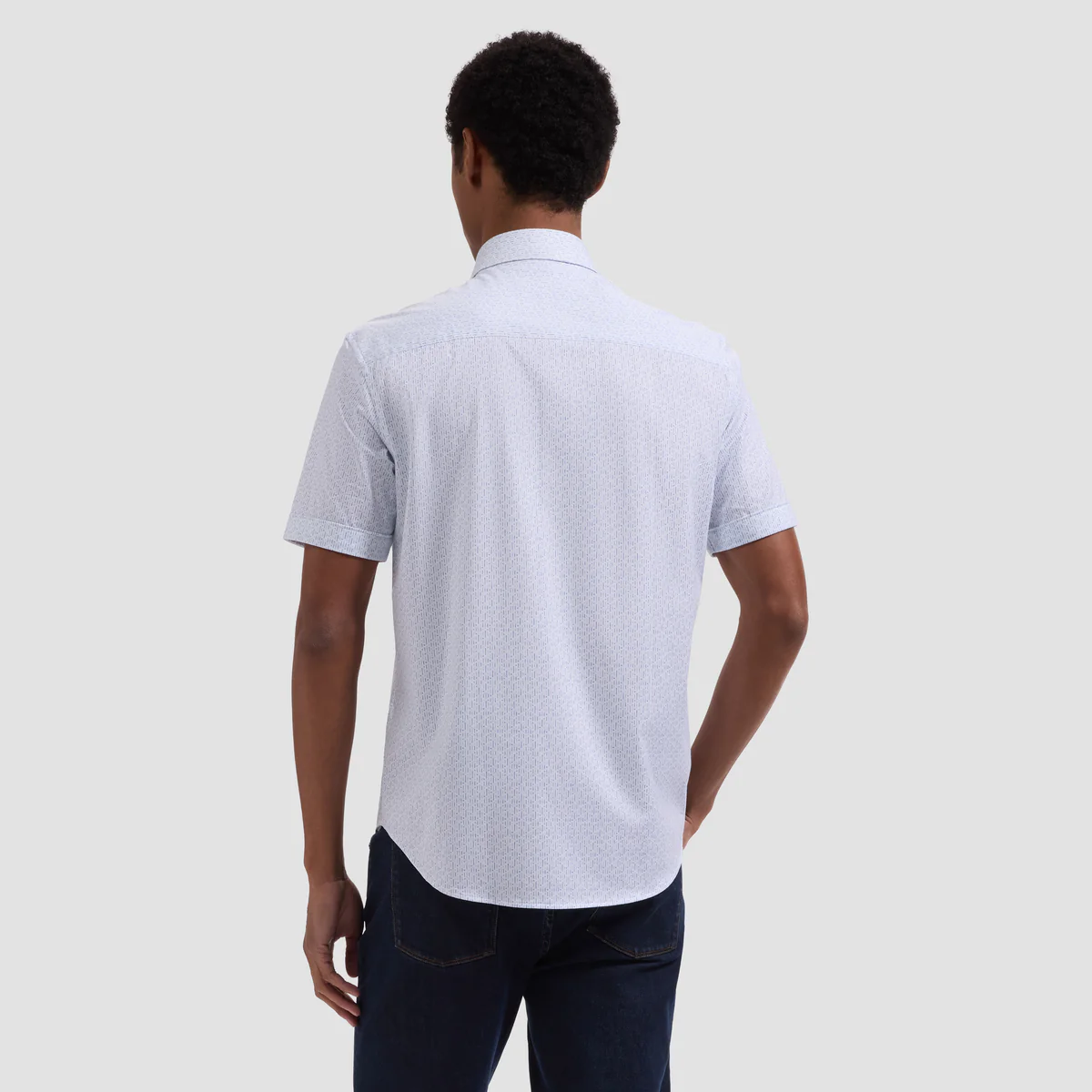 Person wearing a light gray polo shirt with a subtle pattern on a plain background