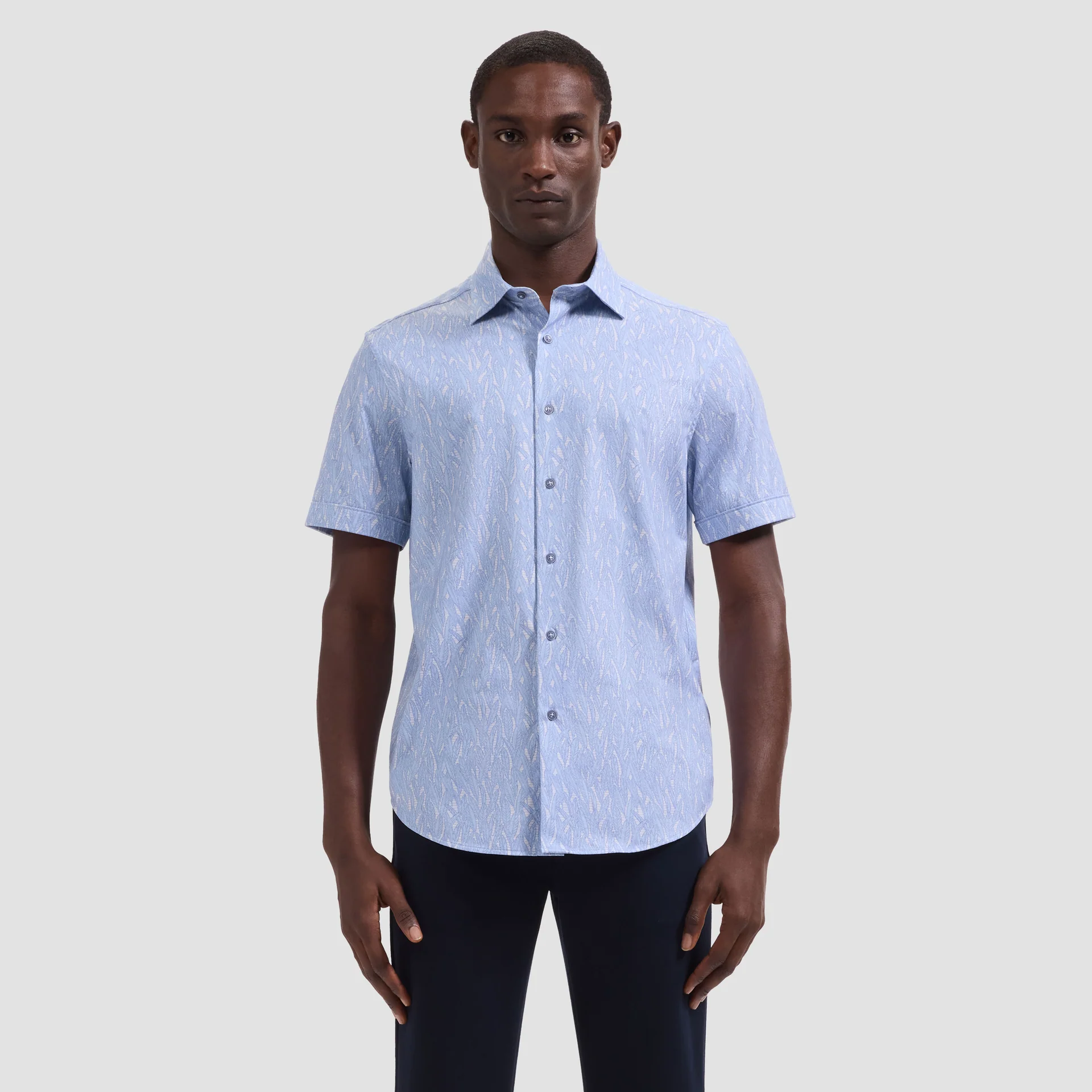 Man wearing a light blue short-sleeve shirt on a plain background
