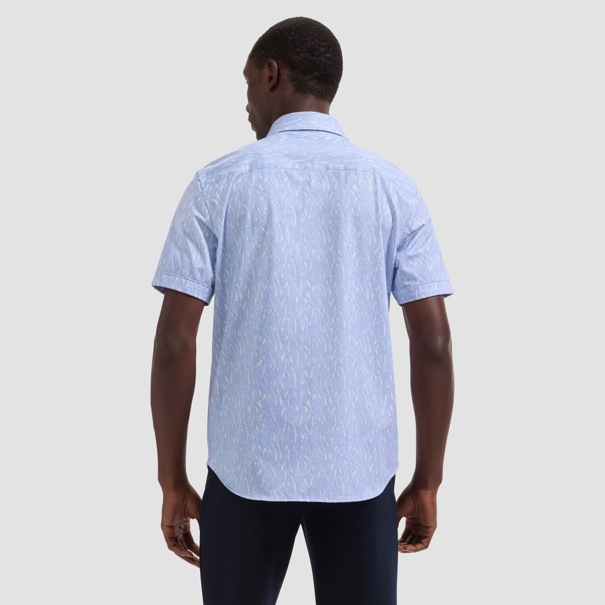 Man wearing a light blue patterned shirt on a plain background