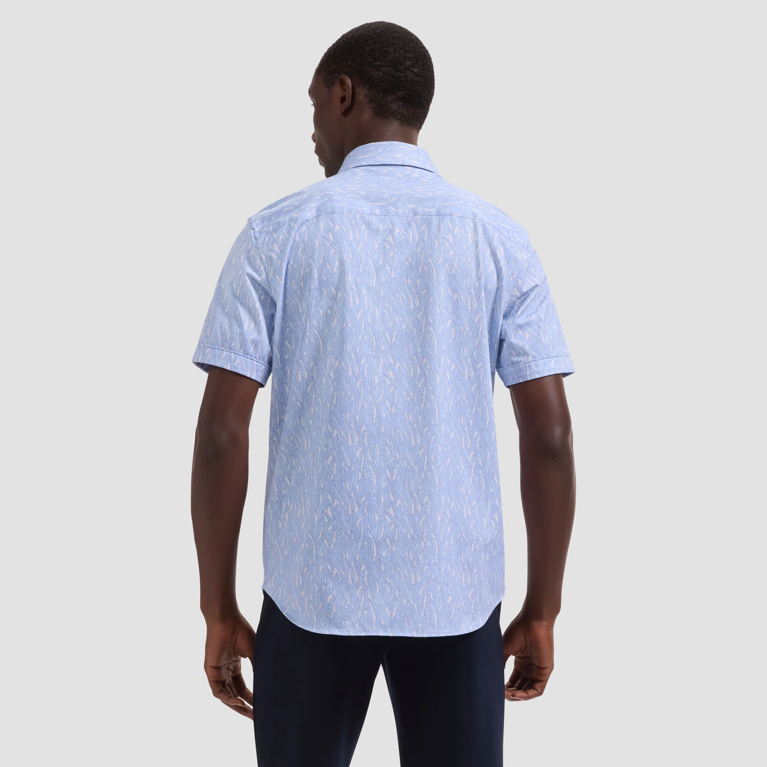 Man wearing a light blue patterned shirt on a plain background