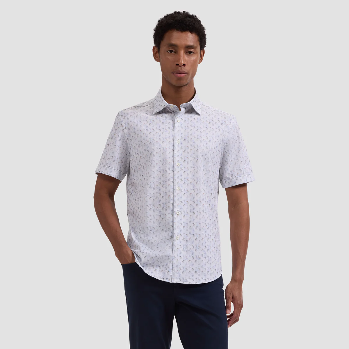 Man wearing a white short-sleeve shirt with a subtle pattern on a light gray background