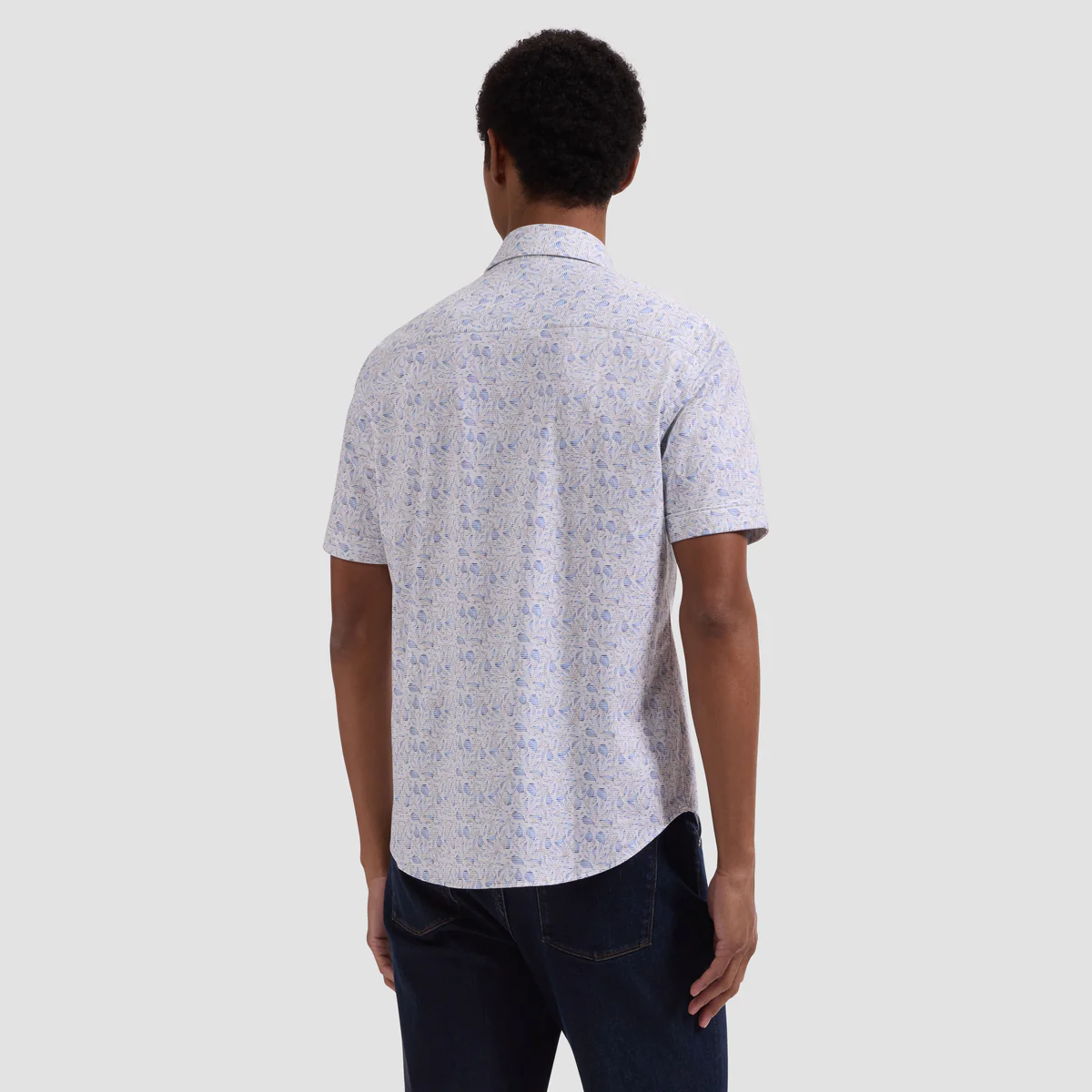 Man wearing a patterned short-sleeve shirt against a plain background