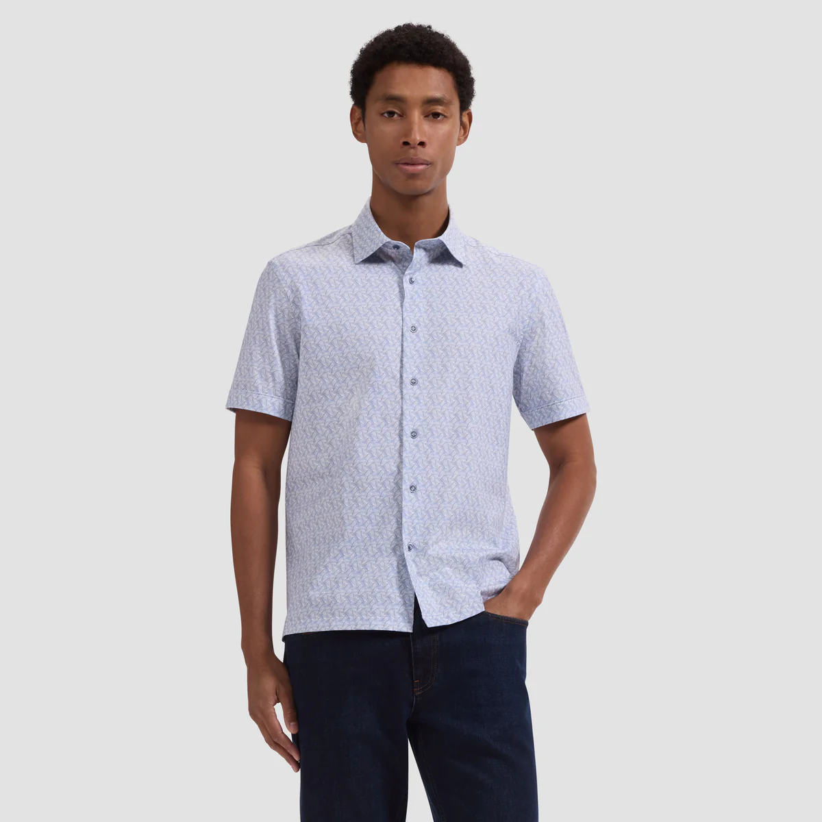 Man wearing a patterned short-sleeve shirt against a plain background