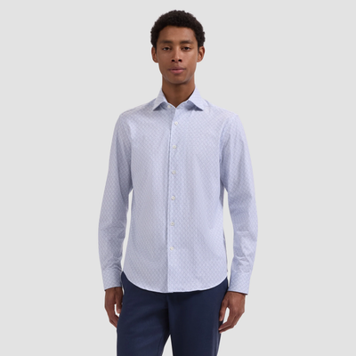 Man wearing a light blue patterned shirt and dark pants on a white background
